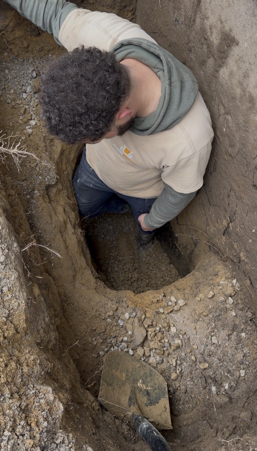 Crew member standing in a deep hand dug window well