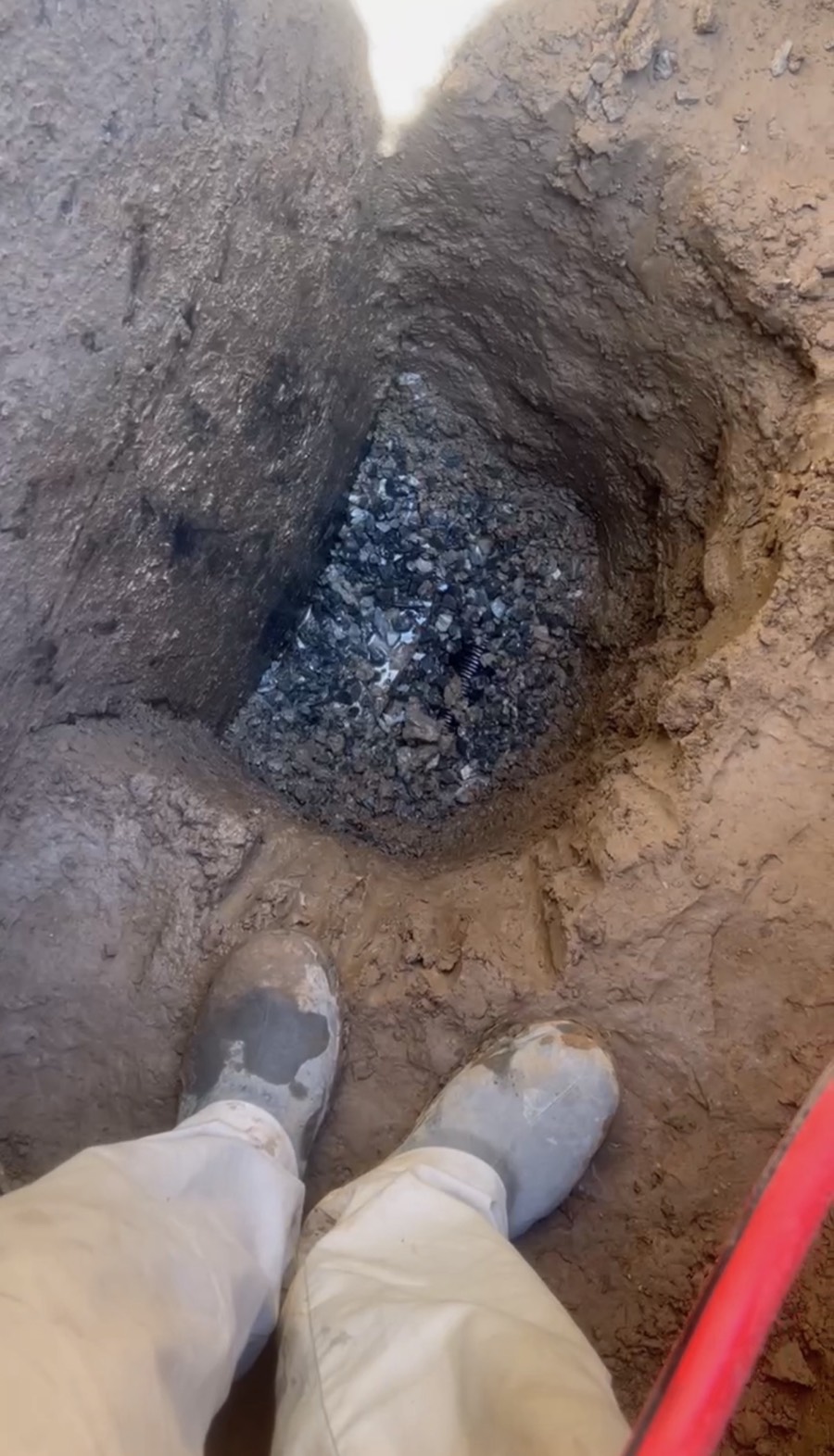 Weeping tile exposed in drainage stone at the bottom of the dig