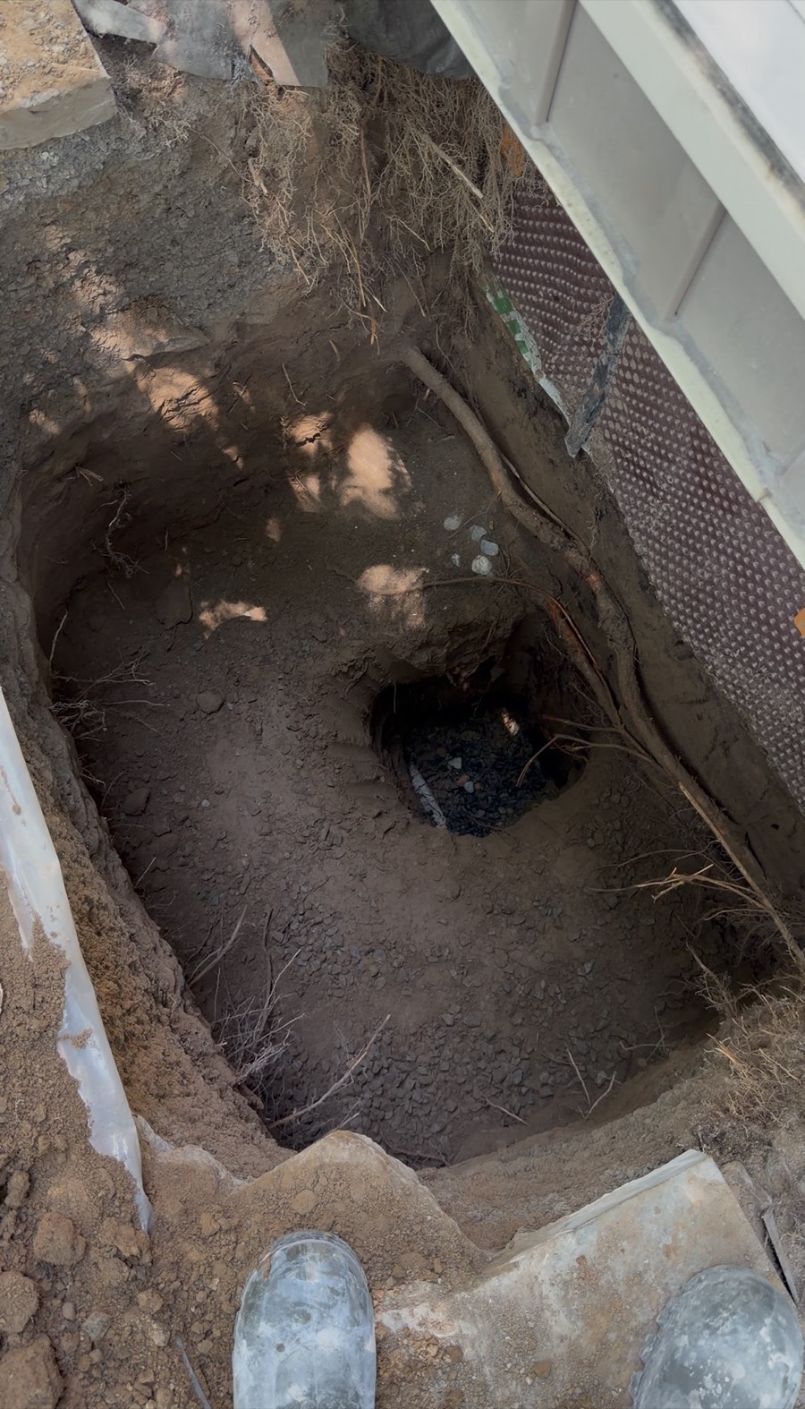 Wide excavation showing foundation membrane and drainage stone pocket
