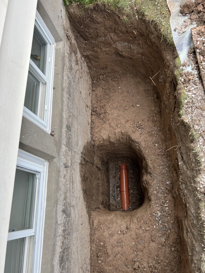 Hand dug trench with the clay drain reached below basement windows